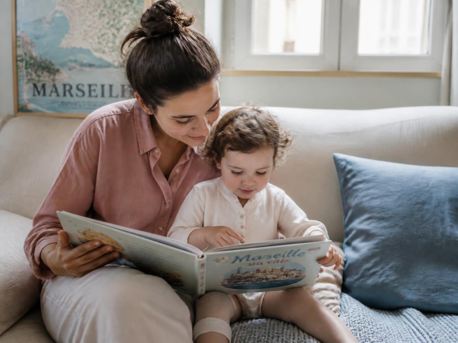 Une intervenante lit un livre avec un jeune enfant dans un salon lumineux à Marseille