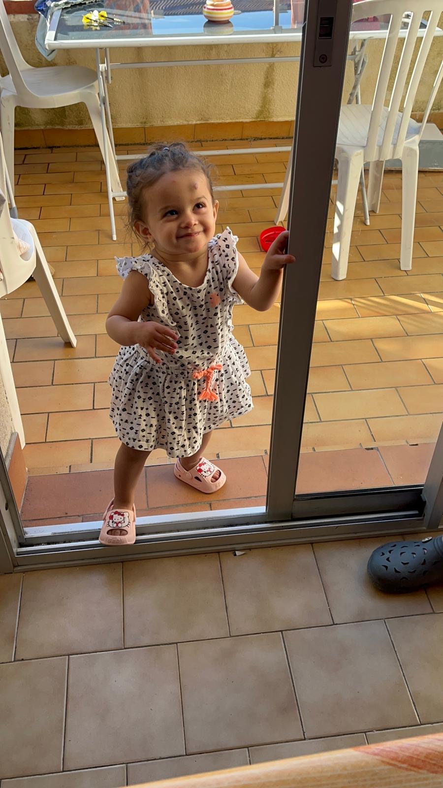 Une petite fille debout près de la baie vitrée