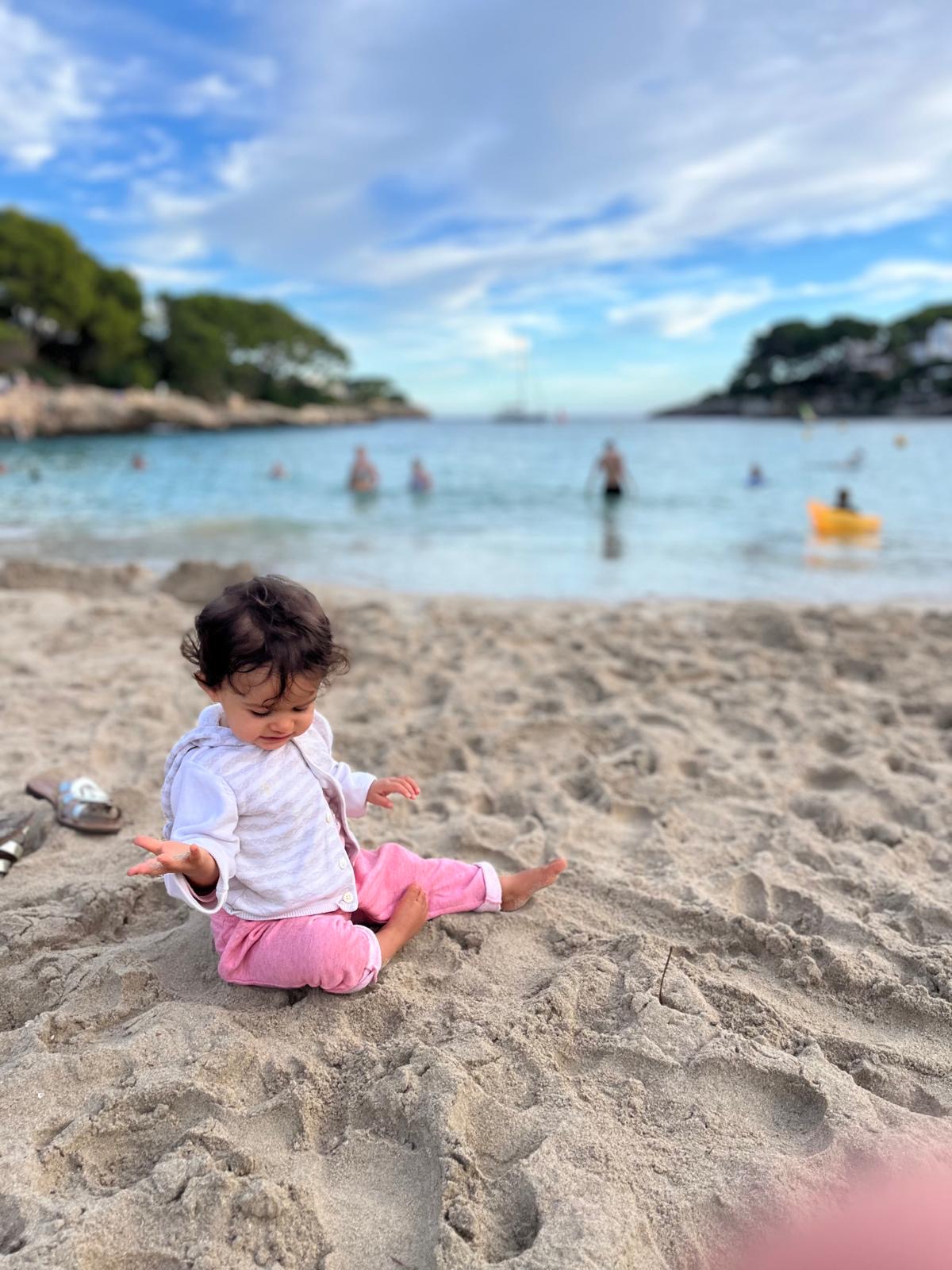 Une petite fille joue dans le sable, au bord d'une calanque